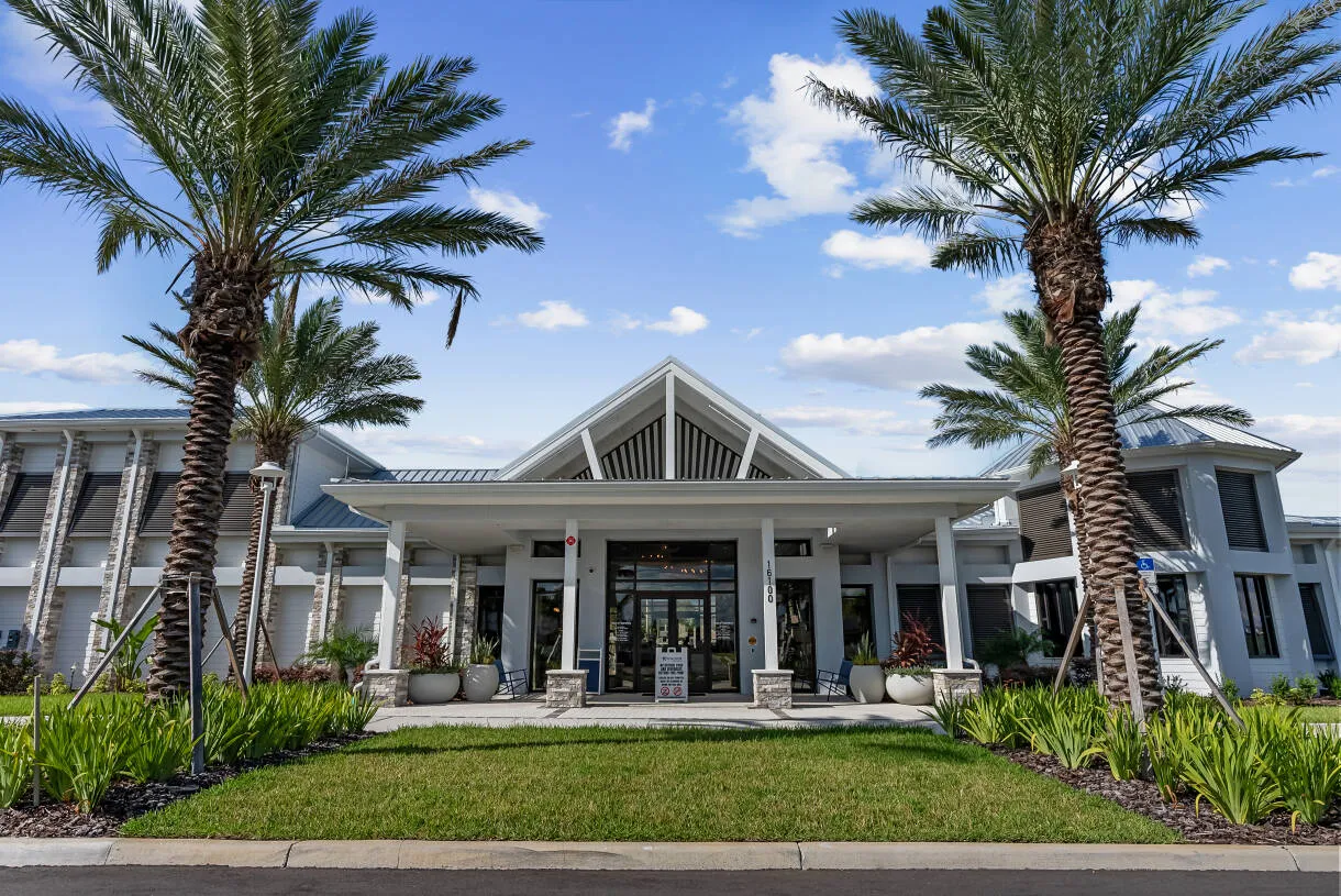 The Reef Club clubhouse exterior at Windsor Cay Resort, framed by palm trees.