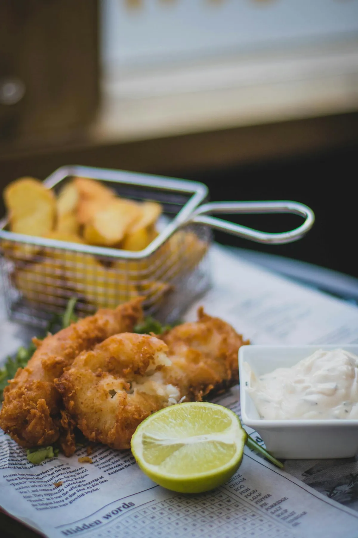 Battered fish and chips with chips, tartar sauce, and a wedge of citrus